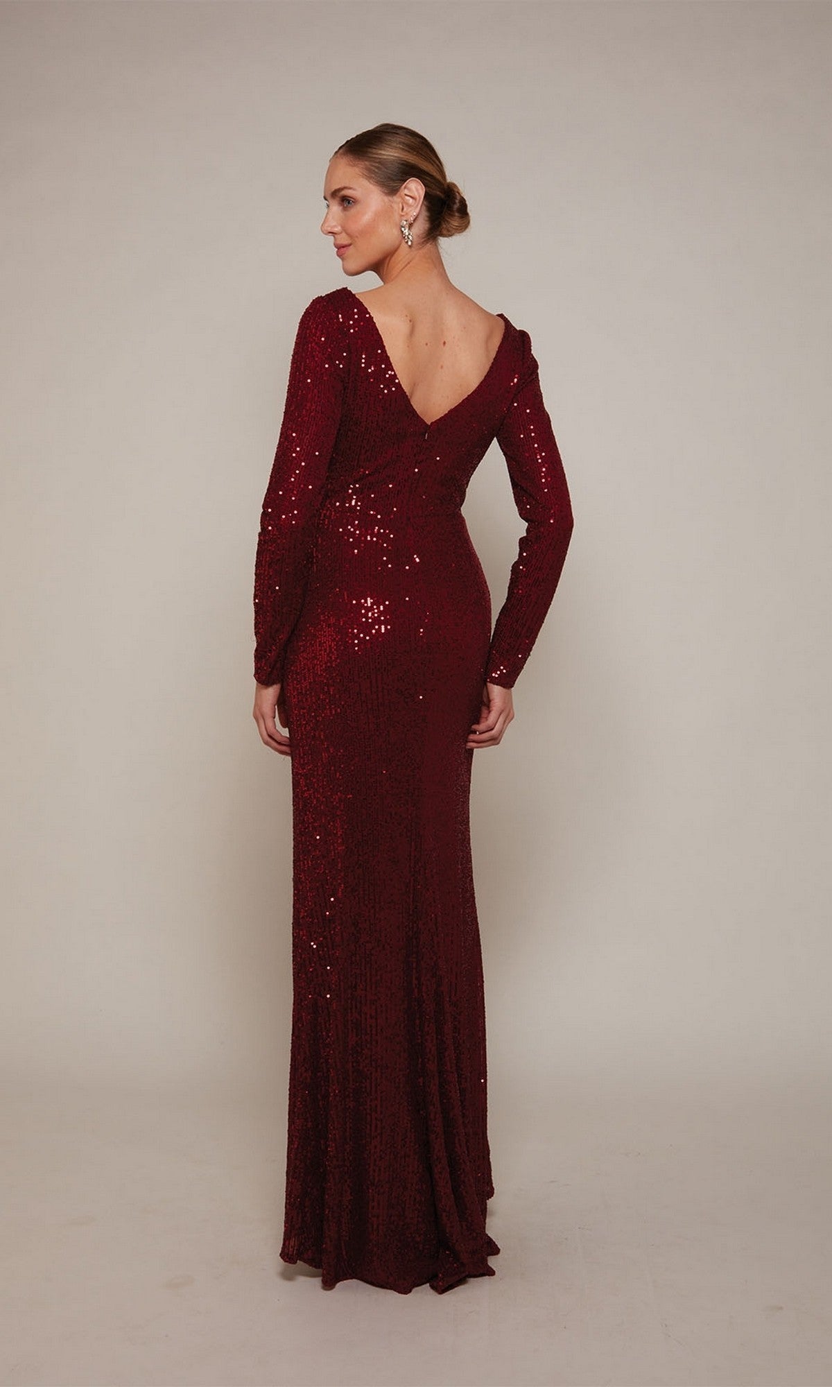 A woman faces away in the Alyce 27688 long-sleeved, floor-length deep red sequin evening dress with a V-back—a stunning choice for a mother-of-the-bride.